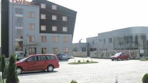 A modern hotel with a flat roof, multiple windows, and a parking lot with several cars. - Plus Hotel (Malu Mare)