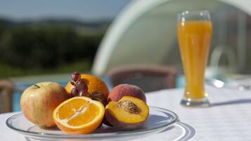 A table with a plate of fruit and a glass of orange juice.