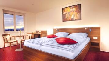 A hotel room with a bed, a desk, a chair, a window with a view, and a painting on the wall.