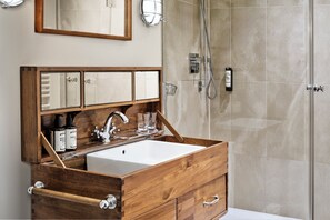 A bathroom with a wooden vanity, a white sink, and a shower area. - ABION Villa Berlin (Berlin)
