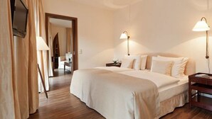 A hotel room with a large bed, two bedside lamps, a wooden nightstand, and a TV on the wall. - ABION Villa Berlin (Berlin)
