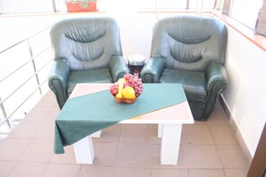 A balcony with two leather chairs, a table with a green tablecloth, and a bowl of fruit. - Sir Lujerului (Bucharest)