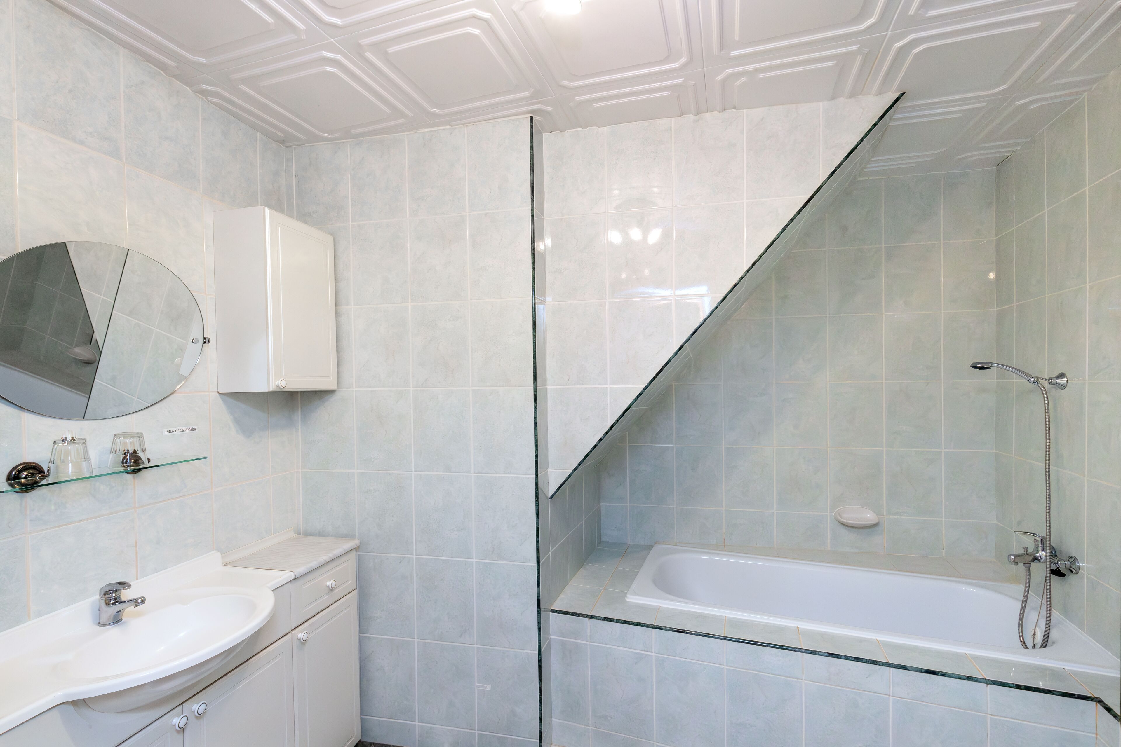 Un baño moderno con cabina de ducha de vidrio, lavamanos blanco y espejo integrado.