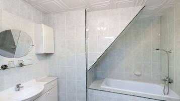 Un baño moderno con cabina de ducha de vidrio, lavamanos blanco y espejo integrado.