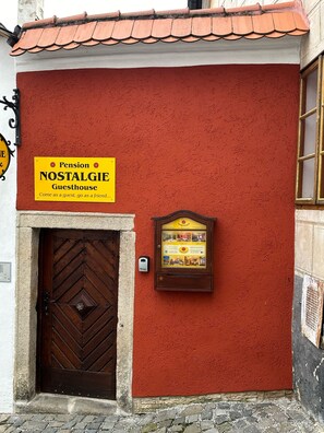 A red building with a sign reading "Pension Nostalgie Guesthouse" and a wooden door. - Pension Nostalgie - Minihotel (Cesky Krumlov)