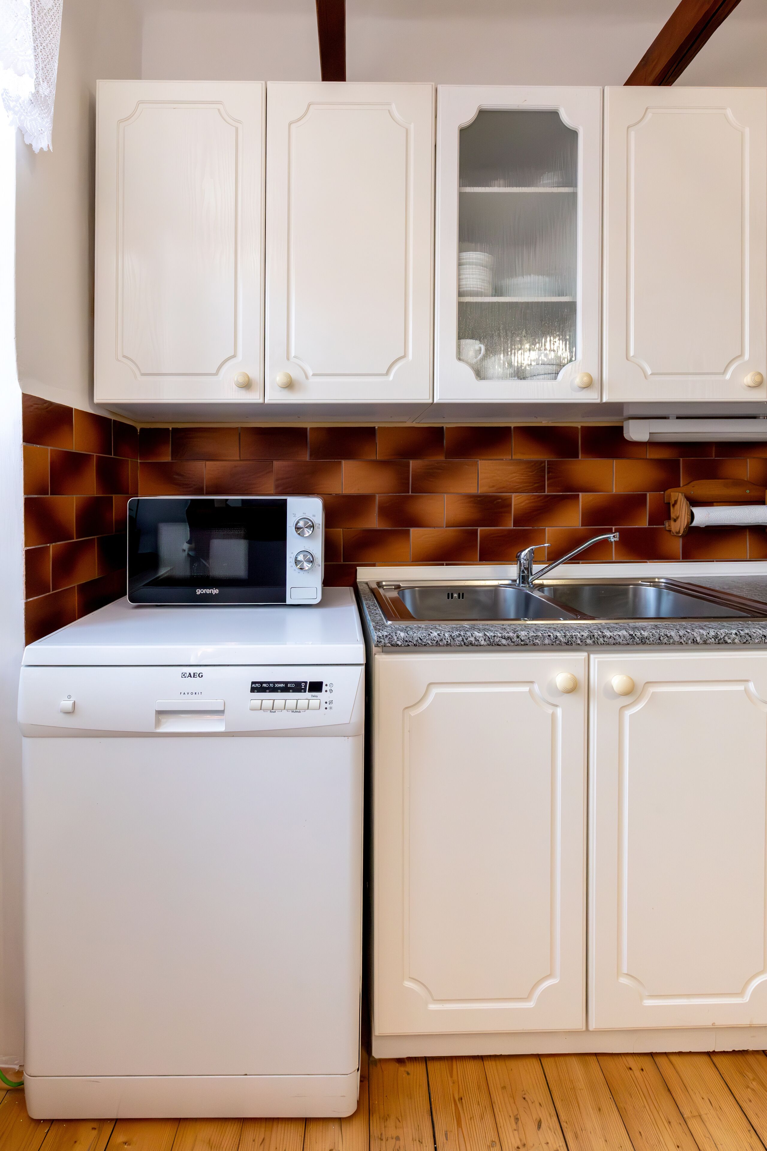 Una cucina con mobili bianchi, un forno a microonde ed una lavastoviglie.