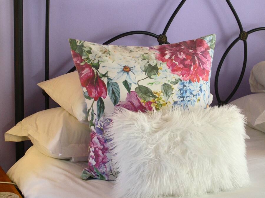 A bed with a floral pillow and a fluffy white pillow.