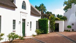 A white building with a green door and windows, surrounded by gravel and small plants. - Rothman Manor Guest House (Swellendam)