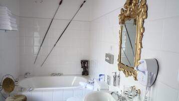 A bathroom with a white bathtub, a toilet, a sink, and a mirror with an ornate frame.