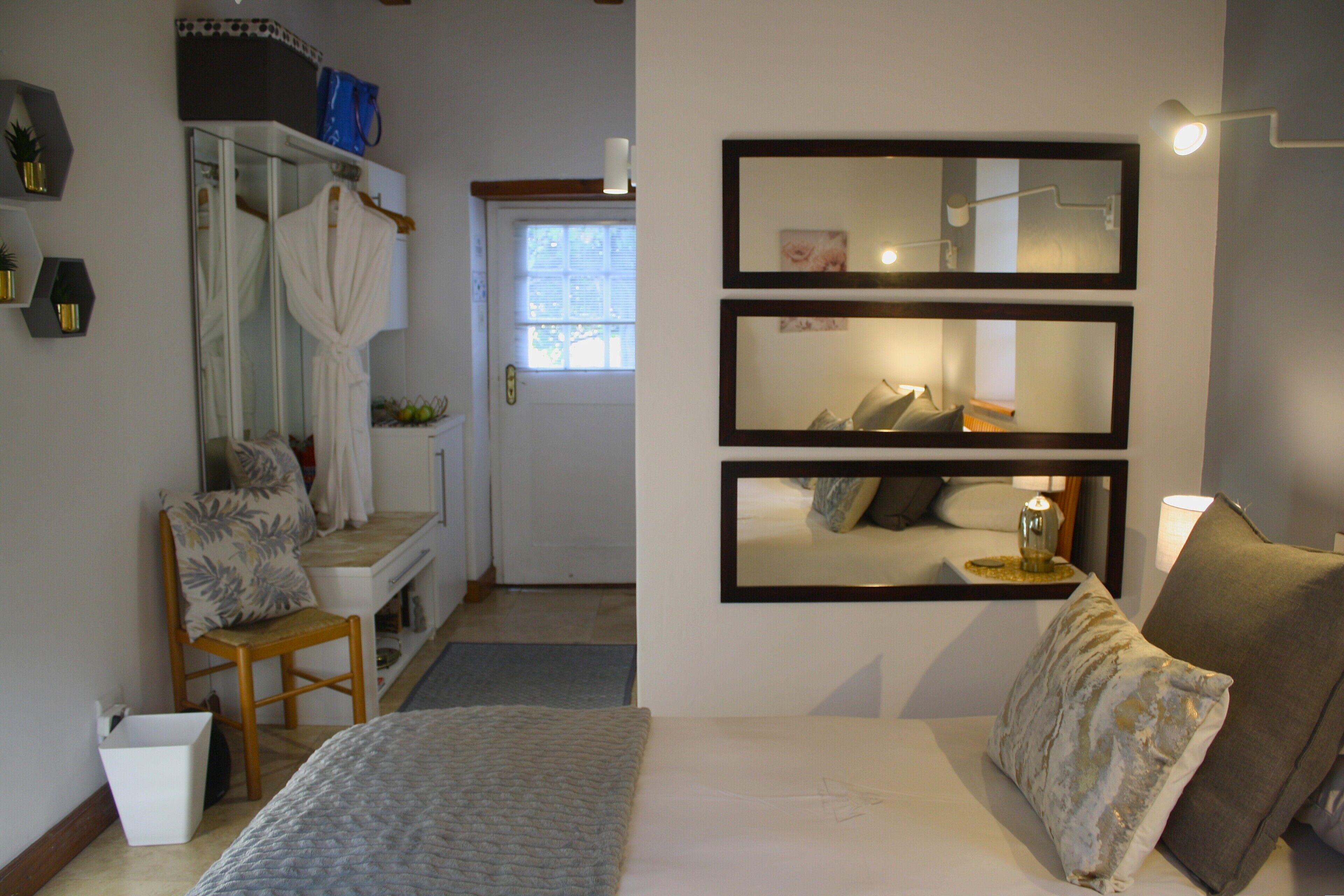 A hotel room with a bed, a chair, a small table, a mirror, and a window.