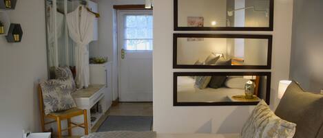 A hotel room with a bed, a chair, a small table, a mirror, and a window.