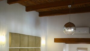 A bedroom with a large bed, a bedside table with a lamp, a patterned rug, and a hanging light fixture. - Rothman Manor Guest House (Swellendam)