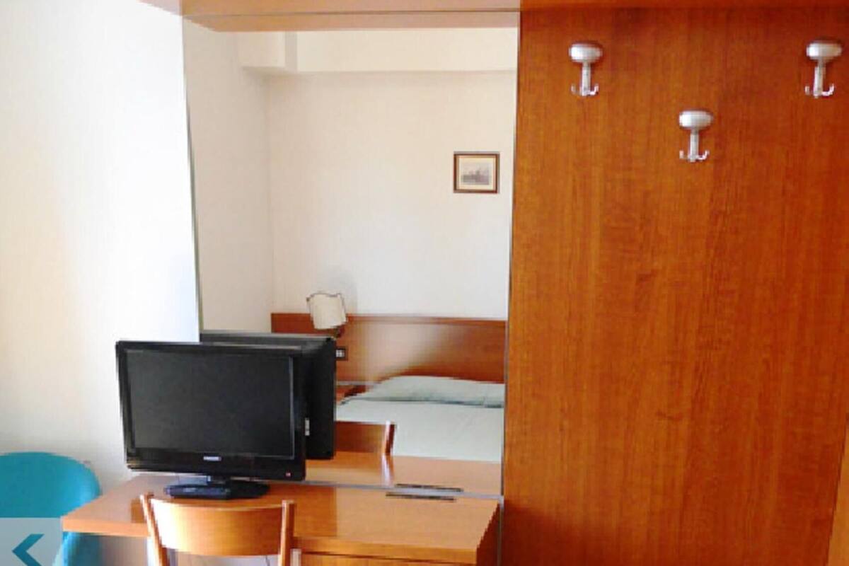 A compact room with a bed, a desk with a computer, a chair, and a wardrobe.