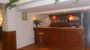 A bar area with a wooden counter, stools, and a potted plant. - Hotel Traghetto (Civitavecchia)