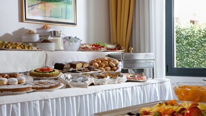 Una mesa de buffet con diferentes opciones de comida, como pasteles, frutas y un bol de ponche de frutas.