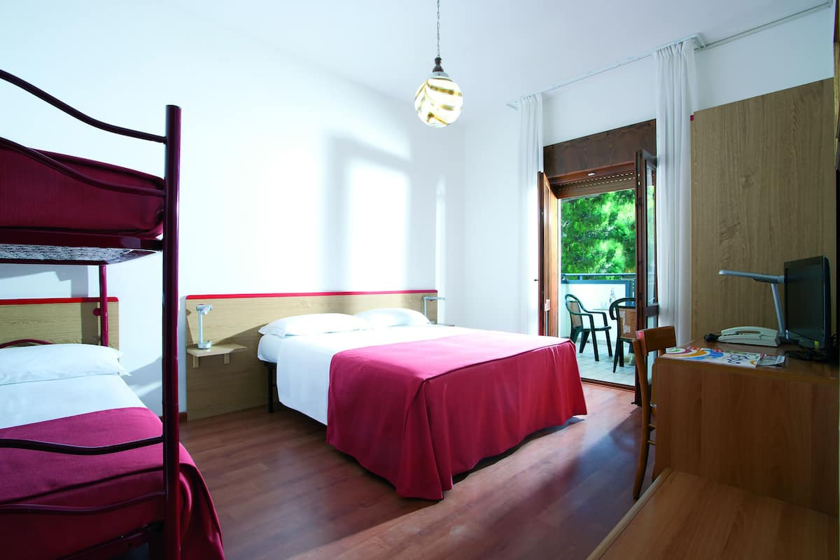 A hotel room with two beds, a desk with a computer, and a view of the outdoors.