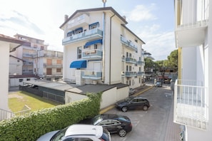 A multi-story residential building with balconies, a parking area, and a clear sky. - Hotel Diana (Jesolo)