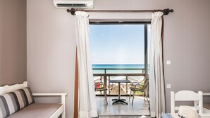Una habitación con una cama, una mesita, una silla y vista al océano.