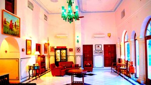 A spacious lobby with a chandelier, seating area, and a reception desk.