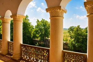 Un balcón con columnas ornamentales y vistas a un paisaje verde.