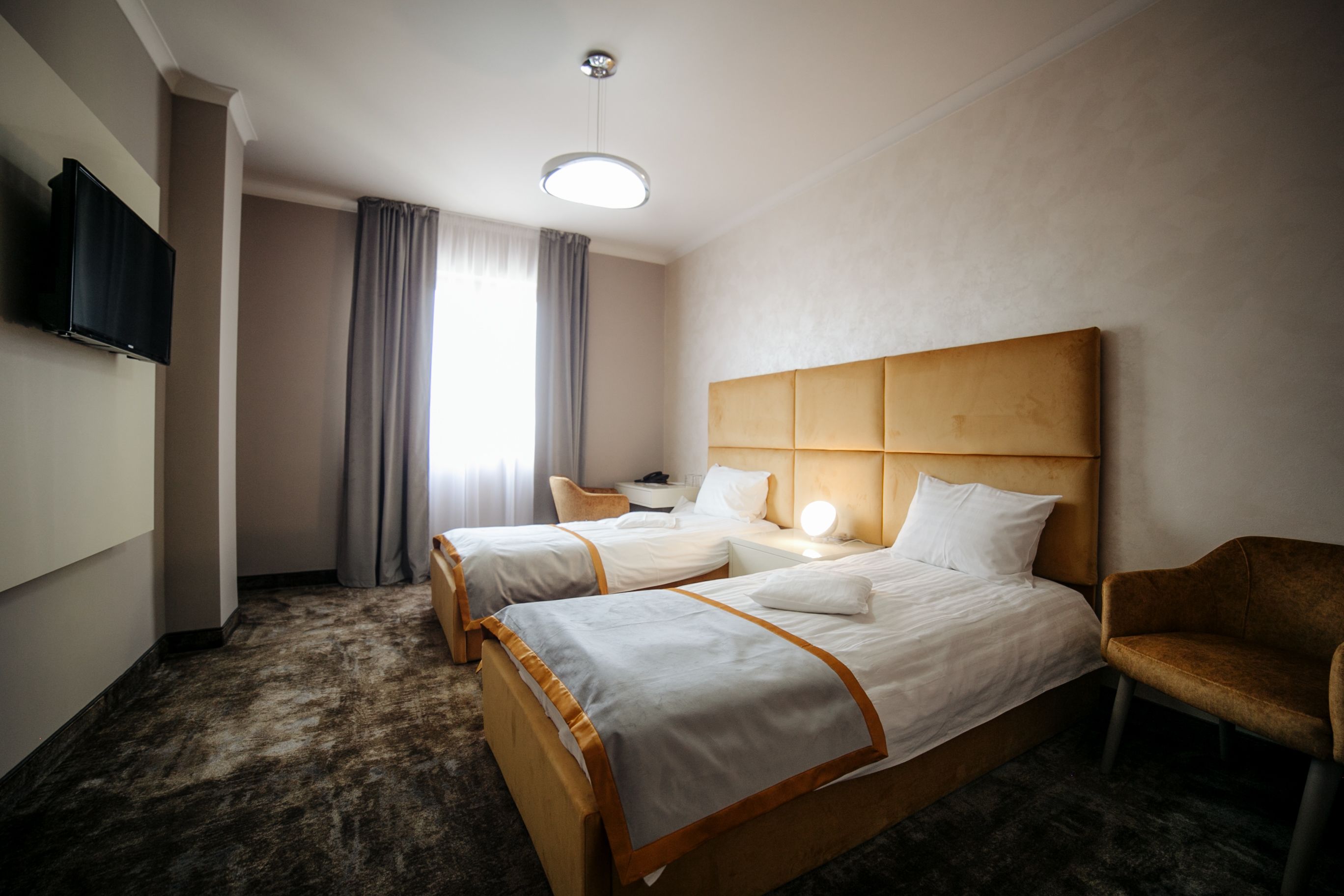 Ein Hotelzimmer mit zwei Betten, einem Schreibtisch, einem Stuhl und einem Fernseher.