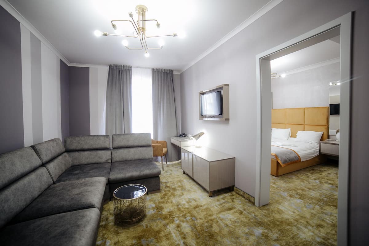 Une chambre d’hôtel moderne équipée d’un canapé d’angle, d’un bureau, d’un lit et d’une télévision.