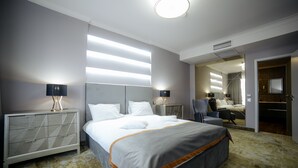 Quarto de hotel moderno com uma cama grande, abajures, um guarda-roupa e um espelho refletindo o ambiente.