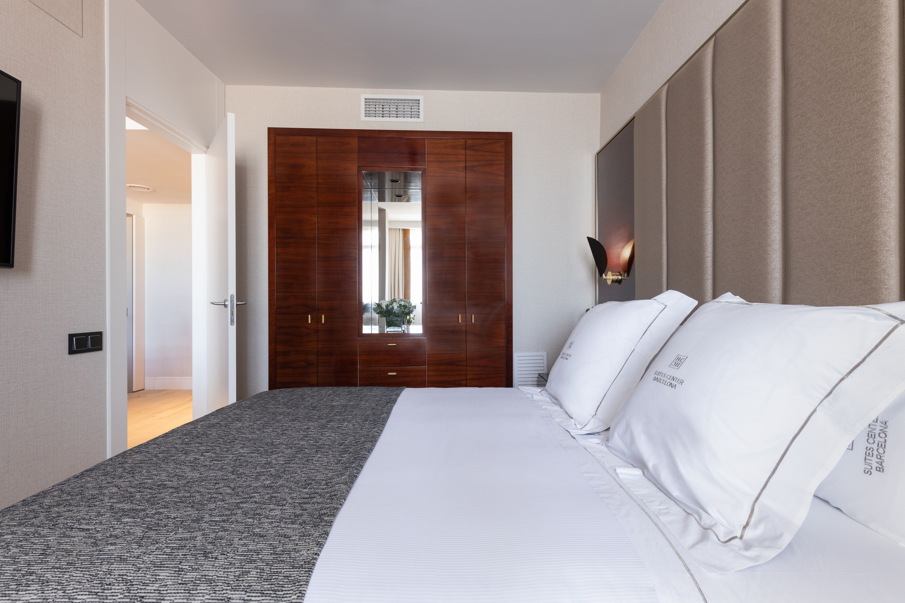Habitació d'hotel amb un llit gran, un armari, un televisor i una finestra que dona a una vista.