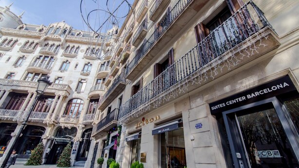 A building with ornate architecture, including balconies and decorative railings. The building has a sign for 'Suites Center Barcelona' and a 'Kiton' store. - Suites Center Barcelona (Barcelona)