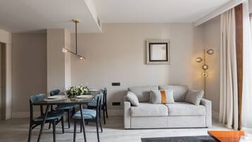 A modern living room with a dining area, featuring a sofa, chairs, a coffee table, and a pendant light.