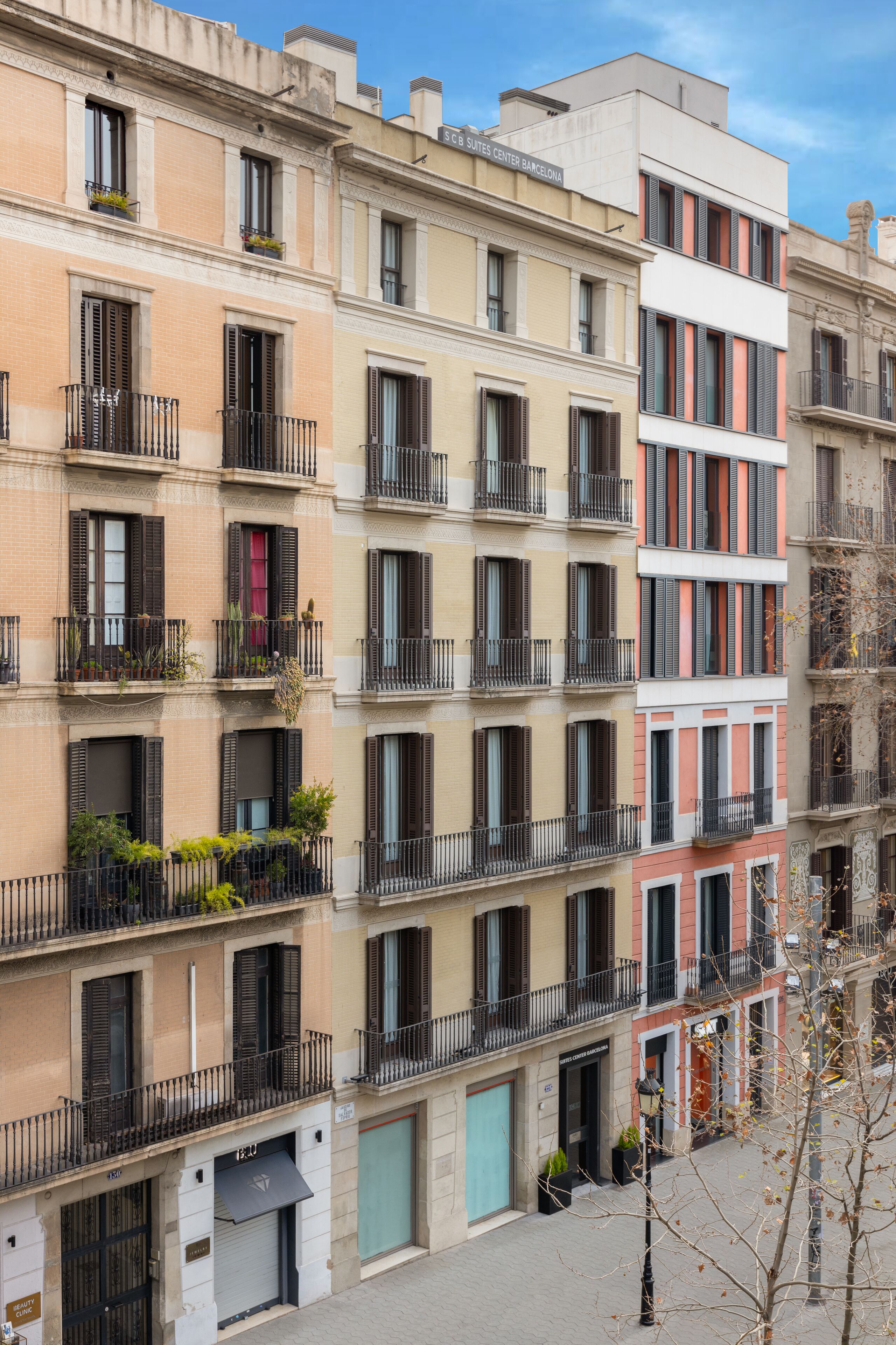 Un edificio de varios pisos con balcones, una tienda en la planta baja y otra tienda cerrada a la derecha.