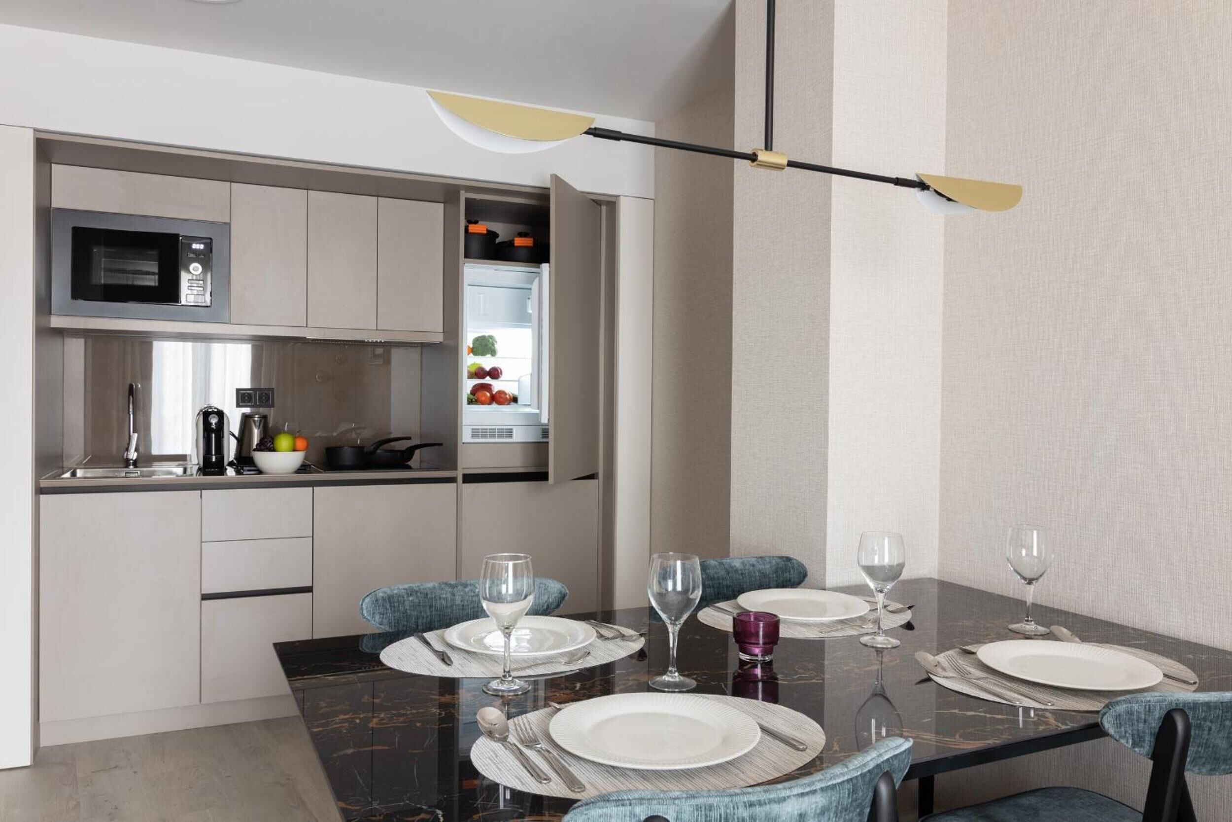 A modern dining area with a marble table, chairs, and a built-in microwave above the counter.