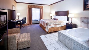 Ein Hotelzimmer mit Bett, Schreibtisch, Stuhl, Fernseher, einem Badezimmer mit Badewanne und einem Fenster mit Vorhängen.