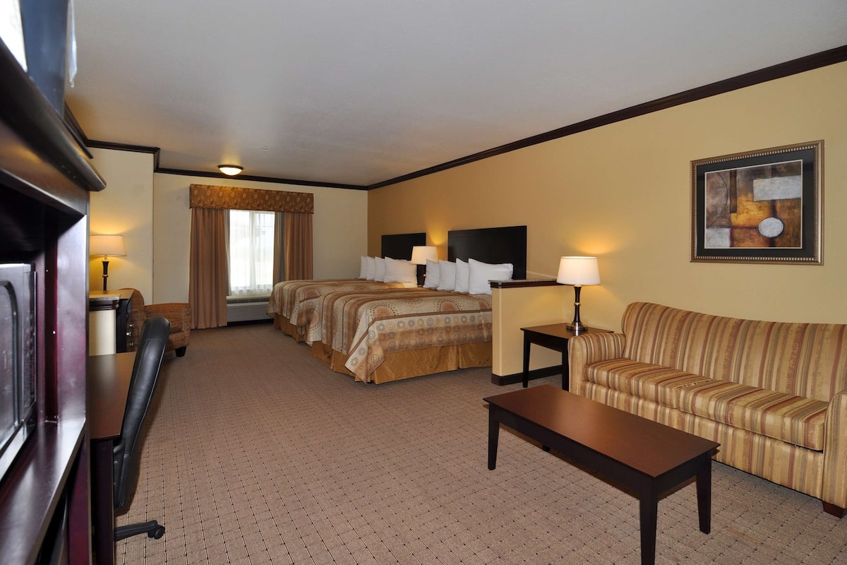 A hotel room with a bed, a sofa, a desk, and a TV.