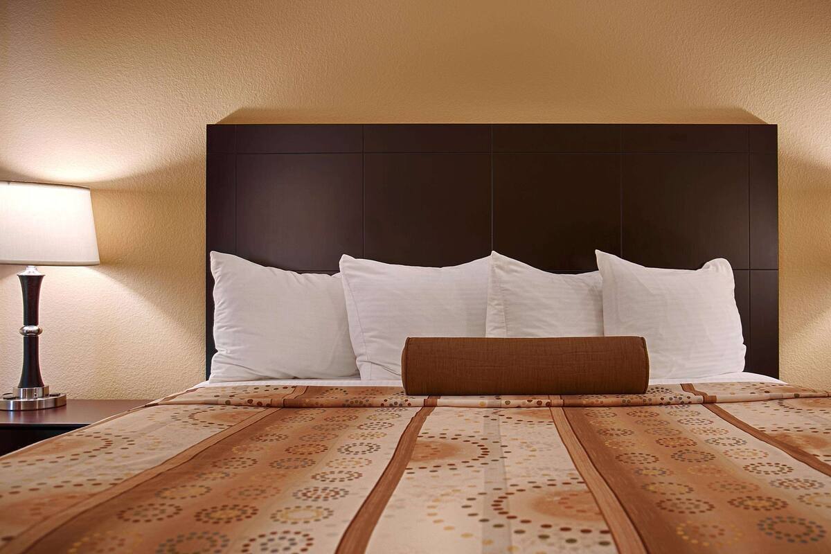 A hotel room with a large bed, two bedside lamps, and a patterned bedspread.