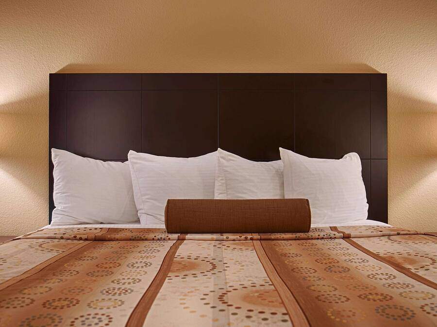 Una camera d'albergo con un letto grande, due lampade sui comodini e una coperta a motivi decorativi.