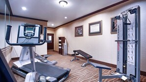 Ein Fitnessraum im Hotel mit Laufband, Hantelbank und Kabelzuggerät.