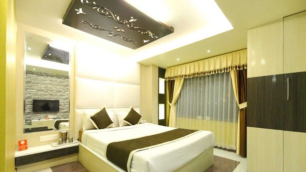 Una habitación de hotel moderna con una cama grande, un televisor montado en la pared, un tocador con espejo y un armario.
