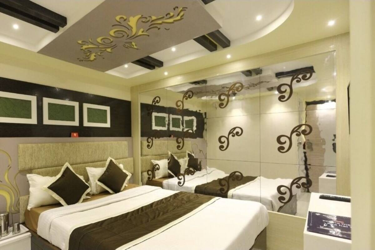 Una habitació d'hotel moderna amb un llit gran, taules de nit, un mirall i panells decoratius a la paret.