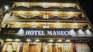 Un edificio de varios pisos con un letrero que dice "HOTEL MANECK" y "MANECK GROUP OF HOTELS".