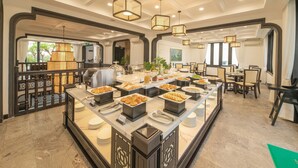 A buffet setup with various food items, a coffee station, and a seating area with tables and chairs. - Hoi An Coco River Resort & Spa (Da Nang)