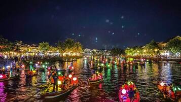 Una escena nocturna de un río con barcos y gente.