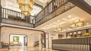 A hotel lobby with a reception desk, a staircase, and a chandelier. - Hoi An Coco River Resort & Spa (Da Nang)