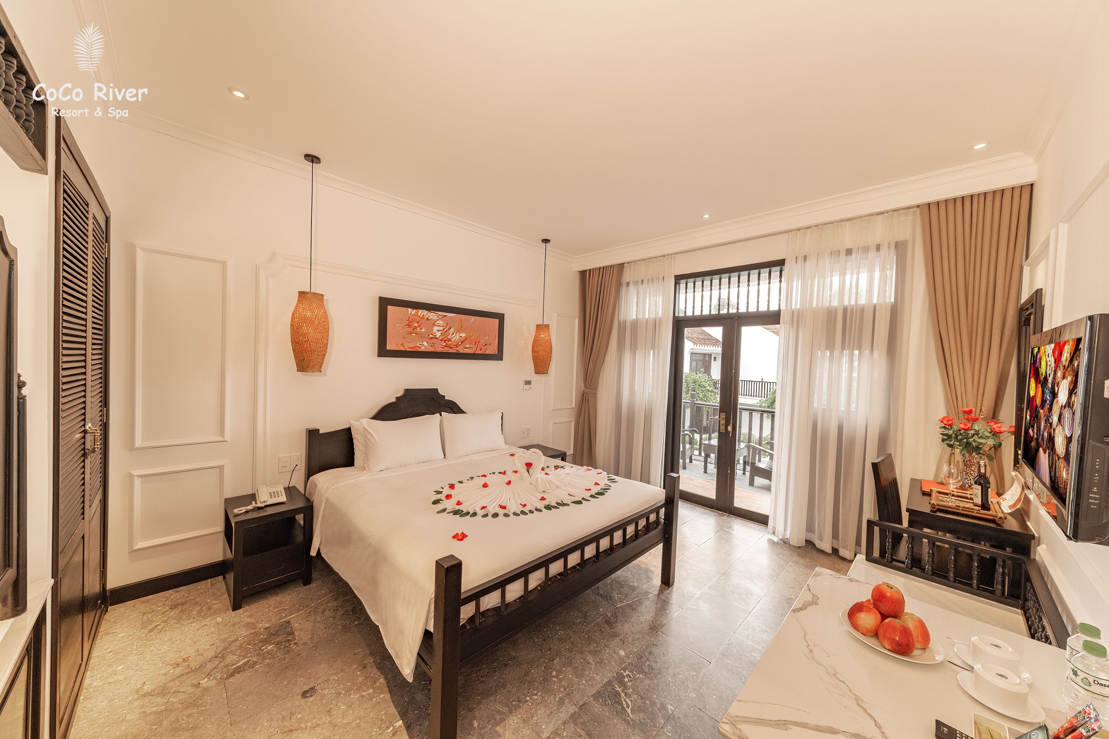 Habitación de hotel con cama, mesita de noche y zona de comedor con mesa lista para el desayuno.