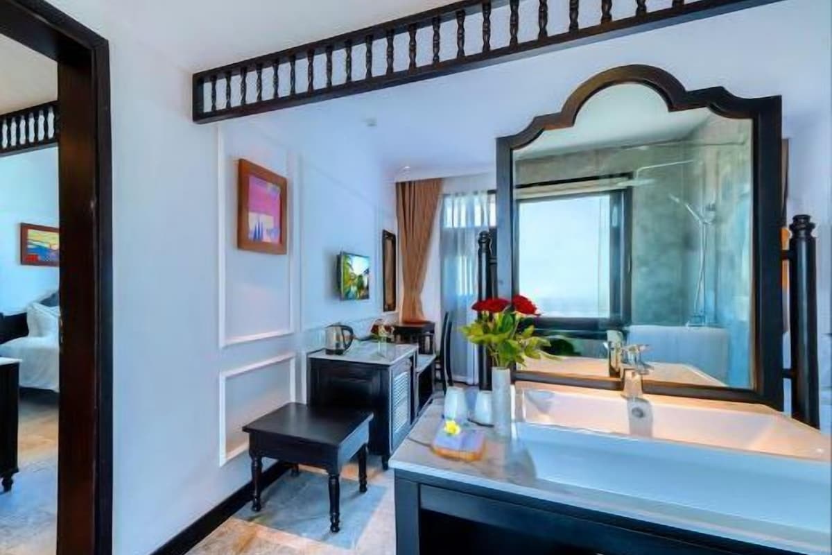 Un baño de hotel con un espejo grande, un lavamanos y un banco.