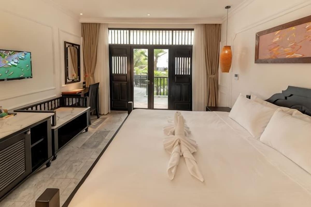 Una habitación de hotel con cama, escritorio, televisor y vistas al exterior.