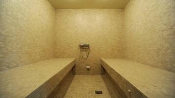 Une zone de douche carrelée, dotée de bancs et d’un pommeau de douche.