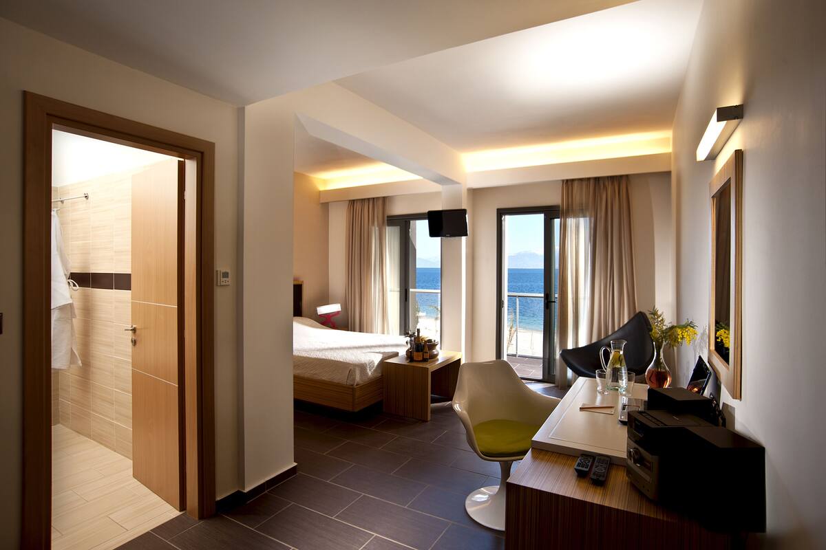 Ein Hotelzimmer mit Bett, Schreibtisch, Stuhl, Fernseher und Meerblick.