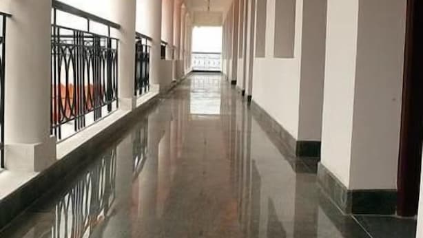 A long, polished corridor with white columns and a reflective floor, leading to a bright, open space. - Apple Valley (Kodaikanal)