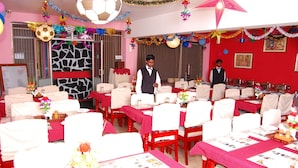 A banquet hall with tables set for a formal event, featuring red tablecloths, white chairs, and floral centerpieces. - Apple Valley (Kodaikanal)